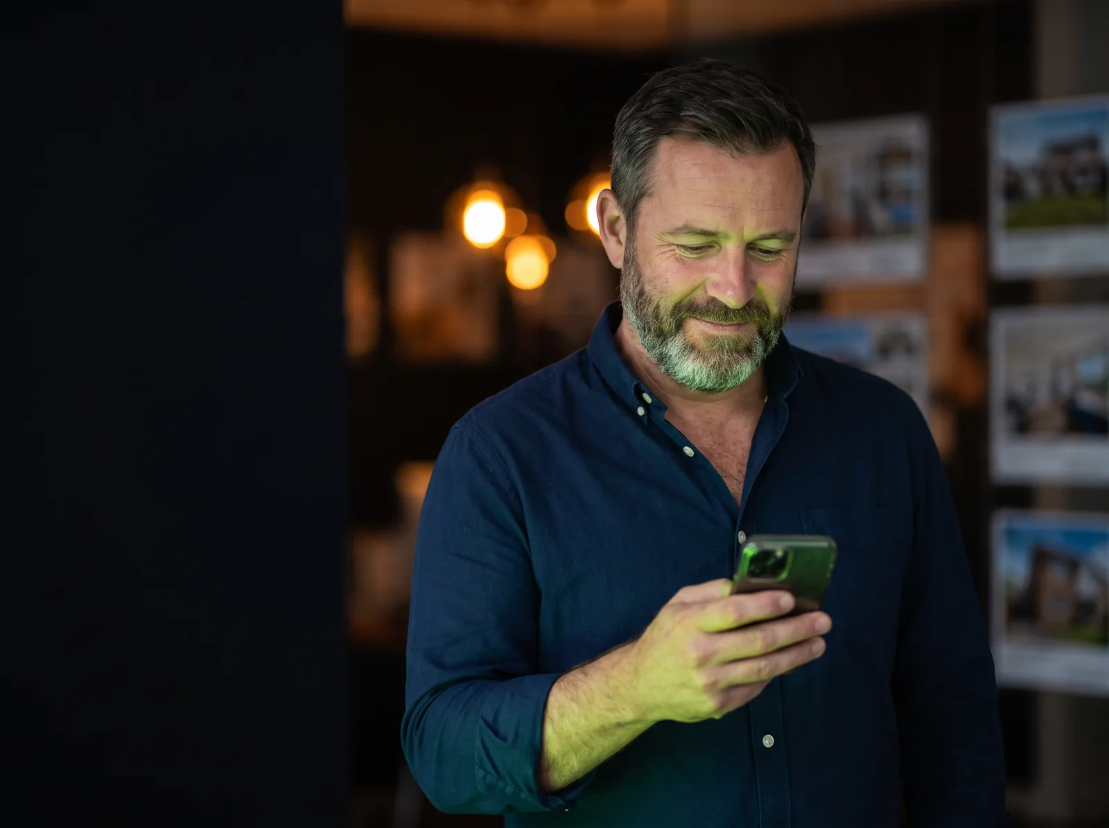 Un directeur d'agence immobilière consulte une proposition d'Arya sur son téléphone, en fin de journée.